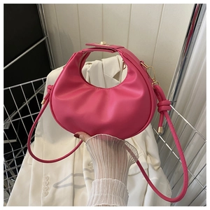 Détail du sac à main croissant rose avec accessoires dorés et bandoulière nouée