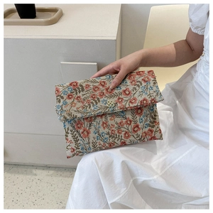 Close-up of vintage floral embroidery fabric and gold flower clasp on envelope clutch bag
