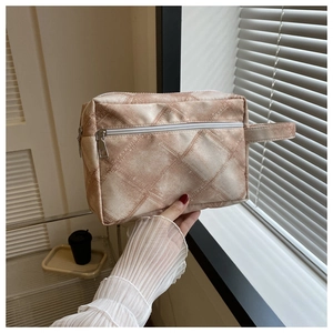 Gros plan détaillé d'une trousse de maquillage beige à carreaux avec fermeture éclair