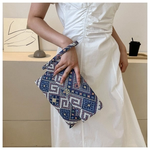 Detailed shot of ethnic woven clutch featuring geometric patterns and golden floral clasp