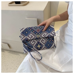 Detail of an envelope clutch with ethnic weave patterns and a gold clover lock