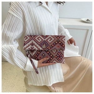Close-up of geometric ethnic woven texture and gold metal logo on envelope clutch bag