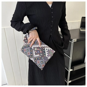 Detail of bohemian geometric woven clutch with vintage gold floral clasp and wrist strap