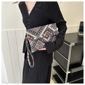 Close-up of geometric woven envelope clutch with colorful pink and orange patterns