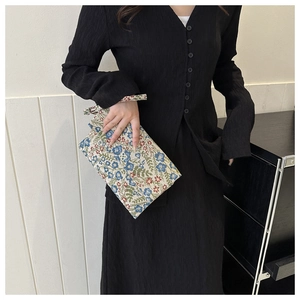 Detail of floral fabric clutch bag with golden flower buckle and wrist strap