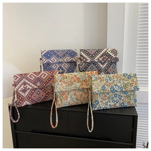 Close-up of woven jacquard envelope clutches with elegant gold floral metal clasps