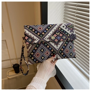 Detail of colorful geometric woven clutch bag featuring a gold clover metal clasp