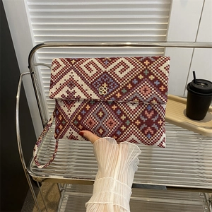 Ethnic bohemian woven clutch bag with geometric pattern and gold flower buckle detail