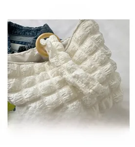 Close-up of white bubble texture fabric and natural round wooden handles on a bucket bag