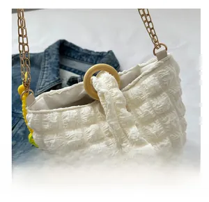 Detail of white bubble texture bucket bag with gold chain and wooden ring handle