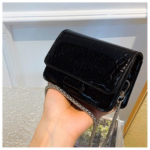 Dettaglio mini borsa nera lucida con stampa coccodrillo e tracolla a catena argento
