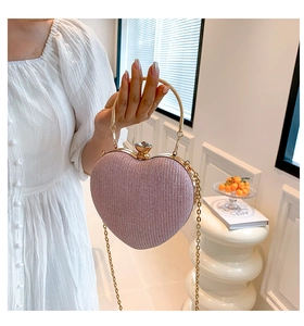Detailed view of pink heart-shaped sequin clutch bag with golden ring handle and rhinestones