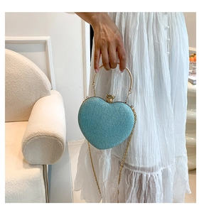 Close-up of heart-shaped glitter evening bag with gold ring handle and chain strap