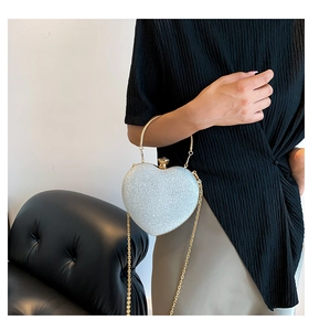 Detail of heart-shaped evening clutch with sparkling silver texture and golden ring handle