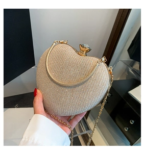 Macro detail of heart-shaped glitter clutch bag with crystal lock and gold chain strap