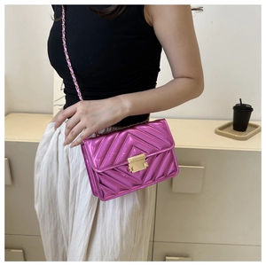 Détail du sac matelassé rose avec coutures en V et bandoulière en chaîne dorée