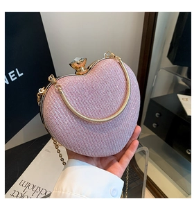 Close-up of heart-shaped glitter clutch with diamond clasp and dual gold chains