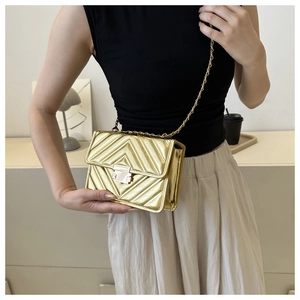 Vue détaillée d'un sac doré à chaîne avec surpiqûres en V et fermoir métallique chic