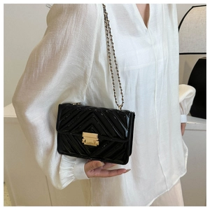 Détail du sac à chaîne en cuir verni noir avec matelassage en V et fermoir doré