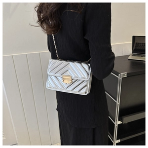 Détail du sac à bandoulière matelassé argenté avec chaîne dorée et fermoir carré