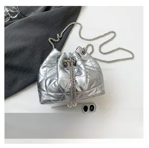 Close-up of silver quilted bucket bag with chain strap next to smartphone for size scale