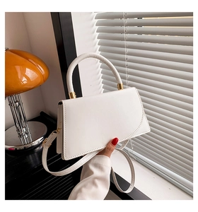 Primo piano di una borsa rettangolare bianca in pelle PU con hardware dorato e manico