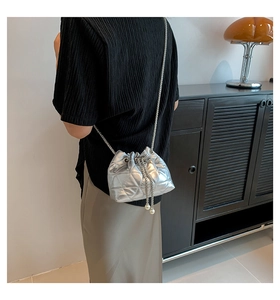 Silver quilted bucket bag with chain strap and pearl drawstring detail on model