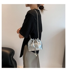 Detail of silver quilted bucket bag with pearl tassels and sleek metal chain strap