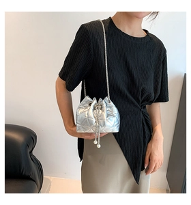 Detail of silver quilted bucket bag featuring a chain strap and large pearl drawstrings