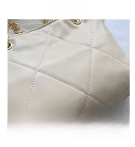 Gros plan sur la texture en cuir matelassé beige et chaîne dorée d'un sac à bandoulière
