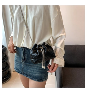 Detail of black quilted leather bucket bag with silver chain strap and pearl drawstrings