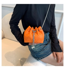 Detail of orange quilted bucket bag with pearl drawstring and silver chain strap