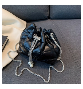 Detail of black quilted leather bucket bag with silver chain and pearl drawstring
