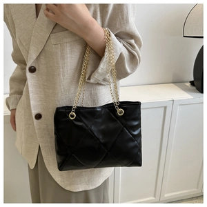 Détail d'un sac bandoulière matelassé noir avec chaîne dorée et texture en cuir luxueuse