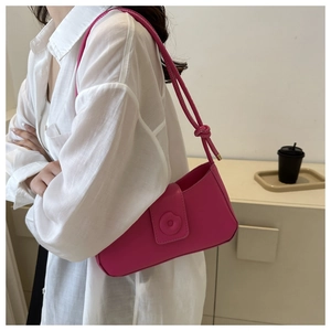 Detail of a bright pink baguette shoulder bag with stylish knot strap and magnetic flap closure