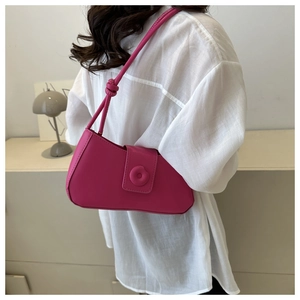 Detail of rose red baguette bag featuring knotted shoulder strap and round buckle ornament