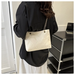 Détail d'un cabas matelassé blanc crème avec bandoulière chaîne dorée sur mannequin