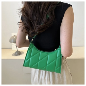 Detail of vibrant green quilted shoulder bag with diamond stitching on a model