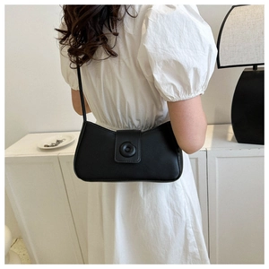 Rear view of model wearing a minimalist black shoulder bag with a round button detail