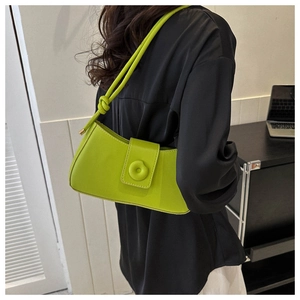 Detail view of bright green baguette bag showing knotted shoulder strap and round buckle