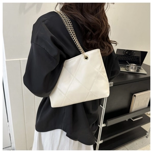 Détail d'un sac bandoulière blanc matelassé en similicuir avec chaîne dorée sur mannequin