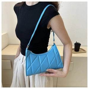 Close-up of a light blue quilted shoulder bag with rhombus patterns and zipper closure