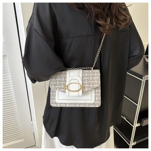 Detail view of a white faux leather and tweed crossbody bag with golden oval buckle