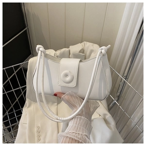 Detail of white minimalist underarm bag with magnetic flap and knotted shoulder straps
