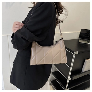 Detail of the diamond-quilted stitching on a beige crescent underarm bag for women