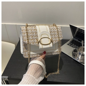 Detail of white tweed crossbody bag with gold chain strap and oval metal buckle