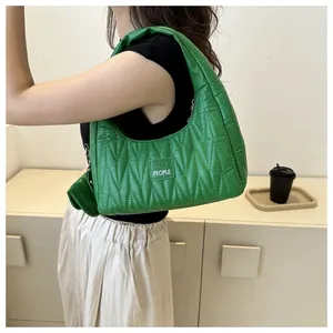 Detail of green quilted underarm bag with Akobia People label and zipper texture