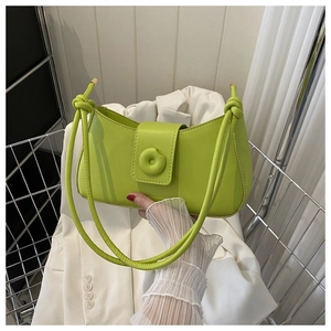 Detail of lime green crescent shoulder bag featuring knotted straps and circular buckle