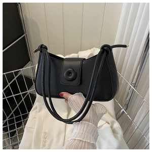 Detailed shot of black crescent underarm bag with knot strap and round decorative buckle