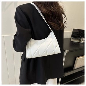 Detailed view of a white quilted half-moon shoulder bag styled with a black blazer